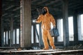 With flashlight. Man dressed in chemical protection suit in the ruins of the post apocalyptic building