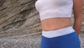 Flat belly girl during diaphragmatic breathing exercises bodyflex on the rock background. Belly close-up view.