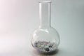 Flat-bottomed round flask with high narrow neck, of borosilicate glass filled with colorful pills