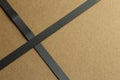 Flat cardboard background with single crossed black tape on the left side Royalty Free Stock Photo