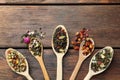 Flat composition with spoons of dried herbal tea leaves on wooden table. Space for text