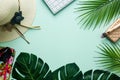 Flat creative frame of tropical nature, palm and Monstera leaves on a pistchio background with laptop, feminine hat, notebook,