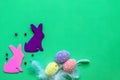 Flat easter composition on green background with eggs and rabbits, place for text