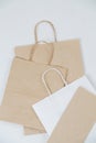 Flat empty brown paper bags on a white surface with rope handles