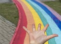 Flat hand on the background of rainbow path on city street, copy space