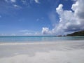 Flat horizon on white sand tropical shore at Ladigue with giant clouds