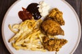 Flat lay above french fries with cheese and fried chicken wings with sauce served on the white plate. Closeup image of served meal