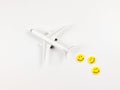 flat lay of airplane model with three yellow circle smiling faces on white background. Happy or fun trip concept