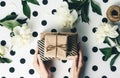 Flat lay arrangement female`s hands holding gift boxes among presents and flowers