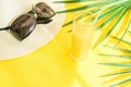 Flat Lay Arrangement of Hat Sunglasses Tall Glass with Fresh Citrus Tropical Fruit Juice Palm Leaf on Yellow Background. Sunlight Royalty Free Stock Photo