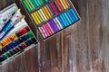 Flat lay art workplace, wooden table with paint brushes, watercolor paints and crayon pastel chalks close up. Copy space