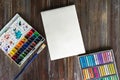 Flat lay art workplace, wooden table with paint brushes, watercolor paints, paper canvas and crayon pastel chalks