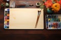 Flat lay of artists tools, watercolors, brushes on a wooden table