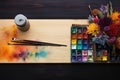 Flat lay of artists tools, watercolors, brushes on a wooden table