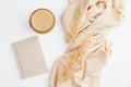 Flat lay autumn composition. Top view beige blanket, cup of coffee, paper notebook and dry flowers on white table. Cozy home