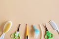 Flat lay on baby care items - scissors, hairbrushes, nasal aspirator and thermometer- on beige background with copy space.