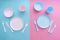 Flat lay baby feeding set. Sippy cup, plate, bowl, cutlery on pastel pink and blue background. Royalty Free Stock Photo