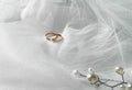 Flat lay background with a pair of gold rings and pearl necklace for wedding or engagement decorated with white lace of a veil of