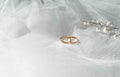 Flat lay background with a pair of gold rings and pearl necklace for wedding or engagement decorated with white lace of a veil of