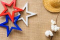 Flat lay background with wooden stars, straw hat and cotton flower on burlap fabric/4th of July background concept
