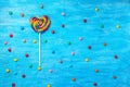flat lay of beautiful colorful lollipop shape heart and scattered sweet bonbons on painted blue wooden background, close up