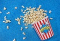 Flat lay of a big paper cup filled with popcorn on a shiny blue surface Royalty Free Stock Photo