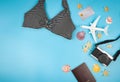 Flat lay of   bikini, camera credit card, passport and airplane model on blue background, decorated with sea shells and Royalty Free Stock Photo