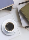 Flat lay of black coffee in ceramic cup on white book with various old textbooks stacks on marble tabletop Royalty Free Stock Photo