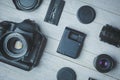 Flat lay with black photoaccessories on white boards: camera, lenses, battery, charger, synchronizer, and lens covers Royalty Free Stock Photo