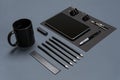 Flat lay of blank black paper sheet, black stationery items and coffee cup on gray desktop. Mock up Royalty Free Stock Photo