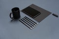 Flat lay of blank black paper sheet, black stationery items and coffee cup on gray desktop. Mock up Royalty Free Stock Photo