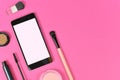 Flat lay with blank black smart phone with empty white screen and  makeup beauty products on pink background with copy space Royalty Free Stock Photo