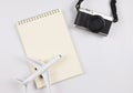 flat lay of blank page opened notebook, airplane model and camera on white background with copy space. Travel, photo and memory Royalty Free Stock Photo