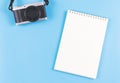 Flat lay of blank page opened notebook and camera on blue background