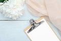 Flat lay blank paper clipboard, beige cloth and peony flowers on rustic blue wooden table. Top view with copy space. Wedding Royalty Free Stock Photo