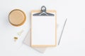Flat lay blank paper clipboard, cup of coffee and office supplies on white table. Top view minimalist style feminine workspace, Royalty Free Stock Photo