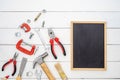 Flat lay of blank space blackboard with construction handy tools over wooden background. Top view with copy space for your