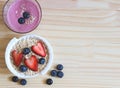 flat lay of breakfast with a glass of blueberry smoothie and oat or granola in white bowl, fresh blueberries, strawberries on Royalty Free Stock Photo