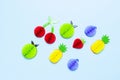 Flat lay bright tropical fruits of paper, strawberry, cherries, pineapple, apple, plum on blue background top view copy space.