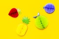 Flat lay bright tropical fruits of paper, strawberry, pineapple, apple, plum on yellow background top view copy space.