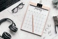 Flat lay of a calendar diary, glasses, clips, stapler, headphones, keyboard, and pencil