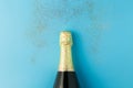 Flat lay of celebration, Champagne bottle on blue background with glitter.