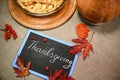 Flat lay. Chalk lettering Thanksgiving on a black board with maple leaves, pumpkin and Thanksgiving pie with flaky crust