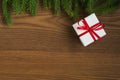 Flat lay christmas background with spruce twigs and white gift box with red ribbon on ash wood surface Royalty Free Stock Photo