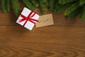 Flat lay christmas background with spruce twigs and white gift box with red ribbon on ash wood surface Royalty Free Stock Photo
