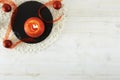 Flat lay Christmas copy space with a red organza ribbon, a red lit candle, a black round limestone plate on light wooden Royalty Free Stock Photo