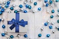 Flat lay Christmas gift with blue ribbon and silver and blue Christmas balls and garland on white wooden background Royalty Free Stock Photo