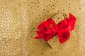 Flat Lay Christmas or Party Background with gold gift box with red bow on golden background. Royalty Free Stock Photo