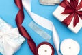 Flat lay with christmas presents, wrapping paper, white and red roll ribbon and crystal isolated on blue background.