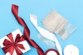 Flat lay with christmas presents, wrapping paper, white and red roll ribbon and crystal isolated on blue background.